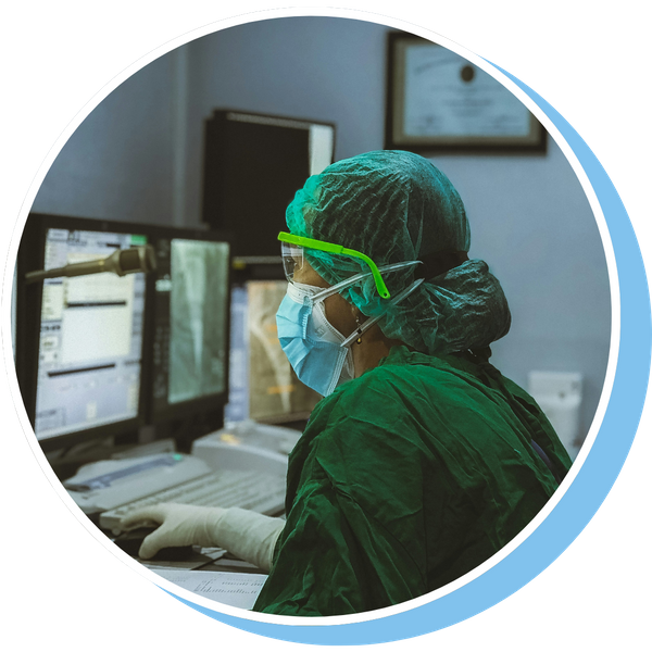 A woman in health scrubs using a desktop setup