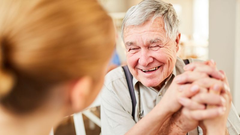 older man smiling and holding hands