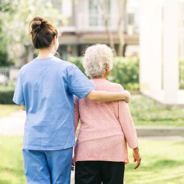 older woman walking outside with home care worker