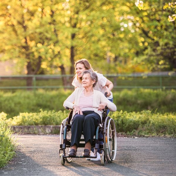 young woman pushing elderly woman in a wheelchair