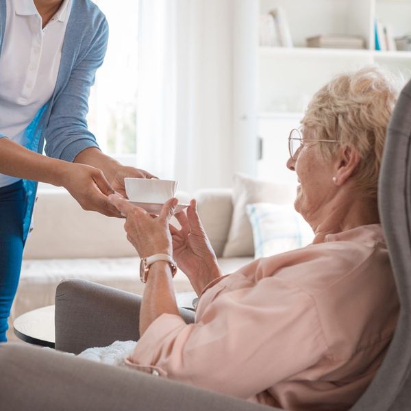 woman handing cup of tea to elderly woman