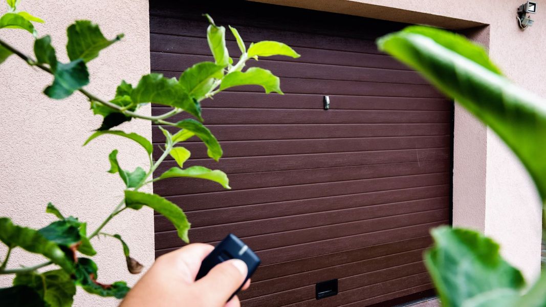 A garage door opener points at a brown garage door