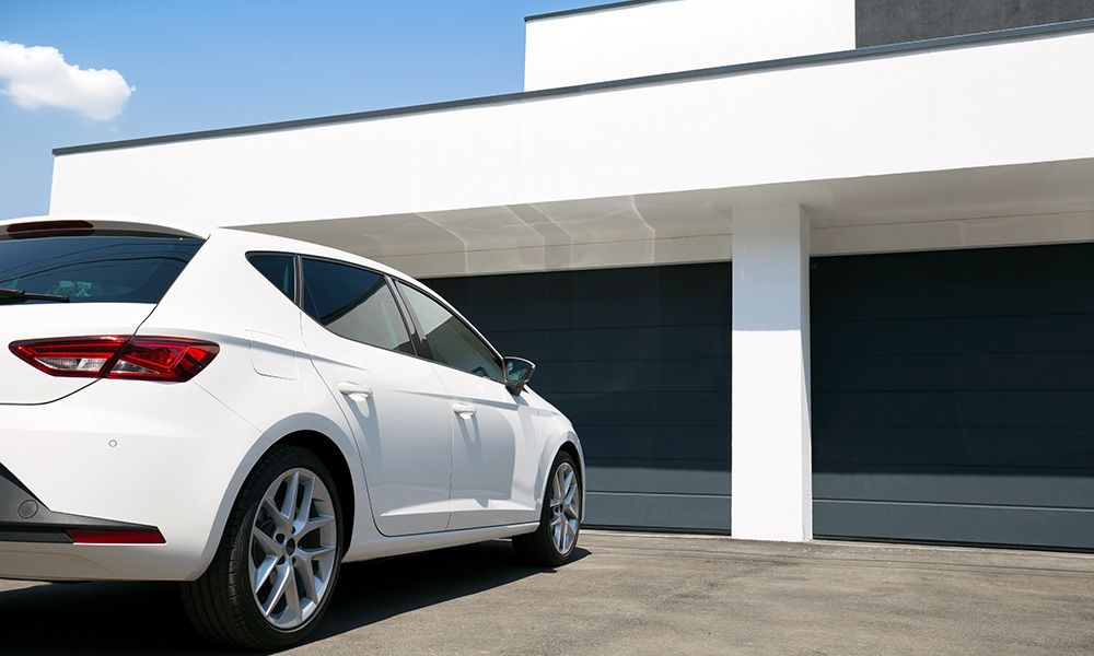 White car in front of green garage doors