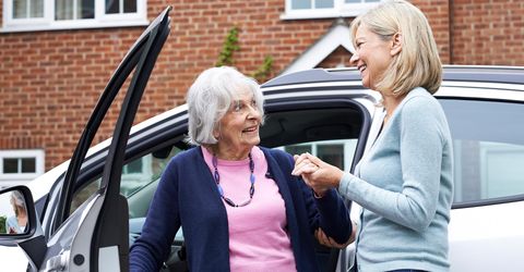 Happy senior women next to car