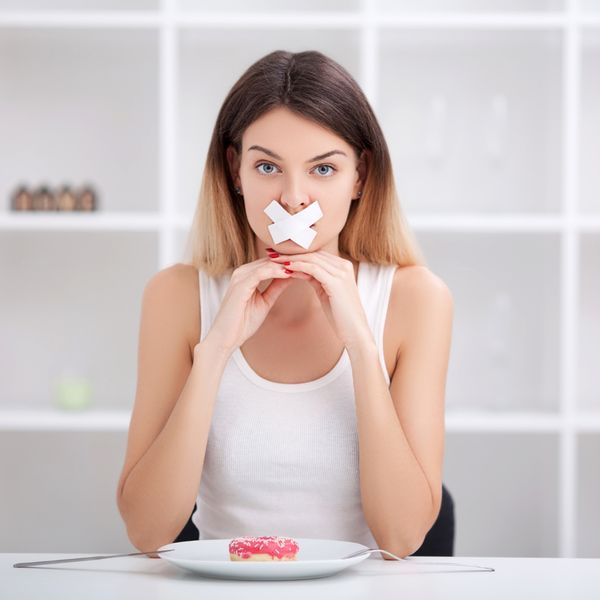 Woman with tape over her mouth and a donut on her plate