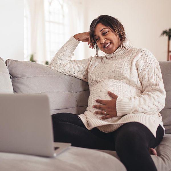Smiling pregnant woman sitting on a couch using a laptop