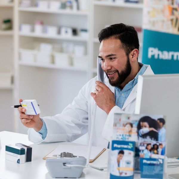Pharmacist talking on the phone and looking at a medication box