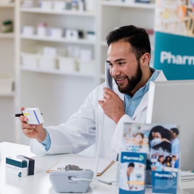 Pharmacist talking on the phone and looking at a medication box