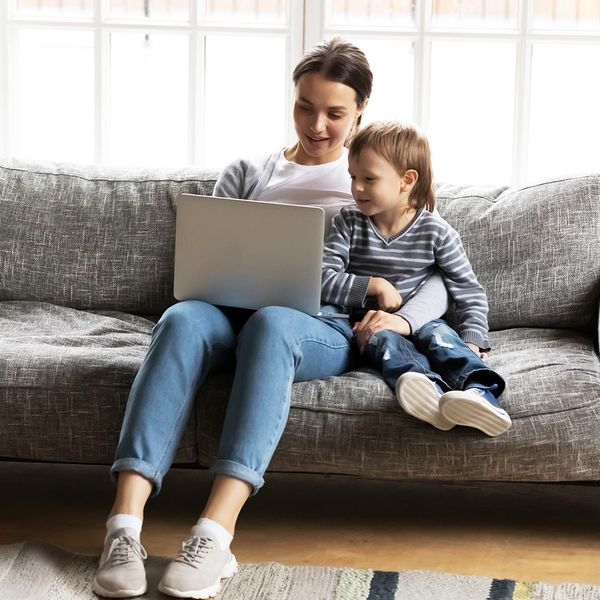 Woman sitting with child on a couch using a laptop