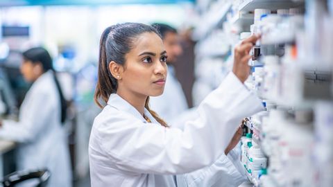 Pharmacist getting medication from shelf