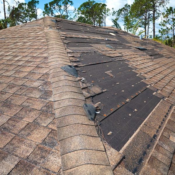 A roof with patches of missing shingles