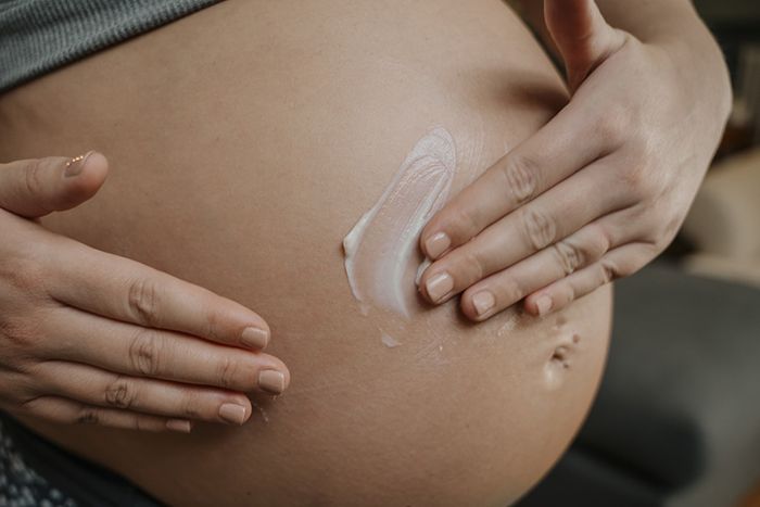 pregnant woman applying glowing tummy butter