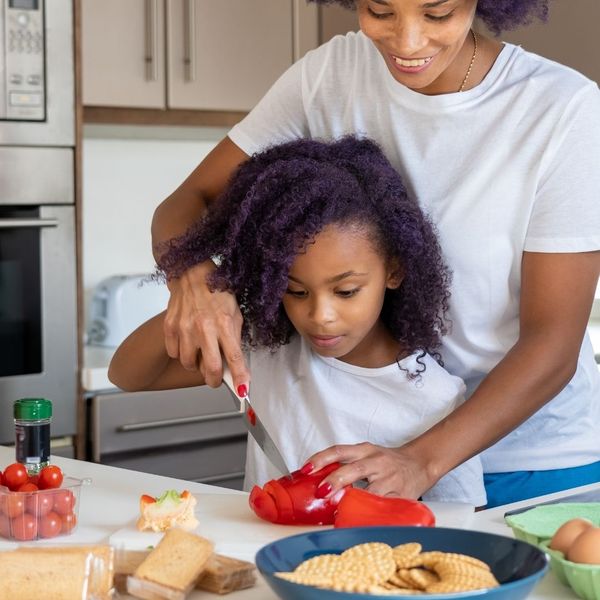 mom and child chopping veggies on countertop 