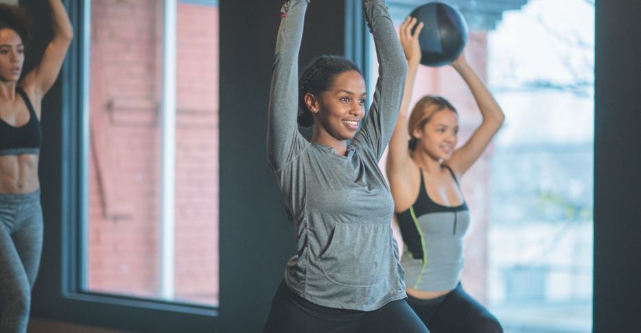 An image of a woman smiling while taking a workout class.