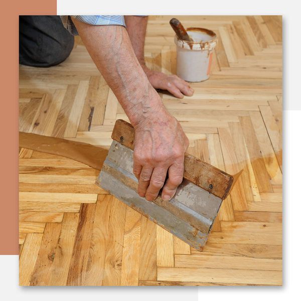 a person scraping wood finisher across a hardwood floor
