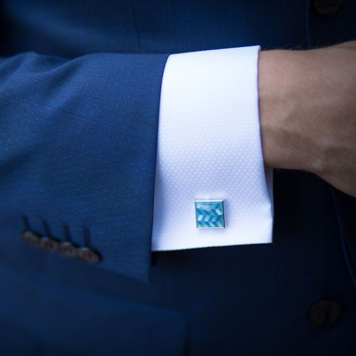a blue patterned cufflink paired with a white shirt and navy suit
