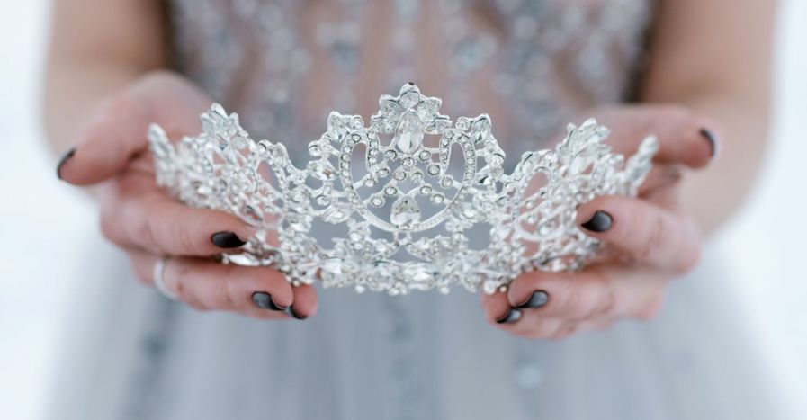 a person in a sparkly dress holding a tiara