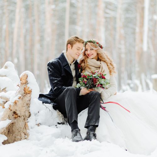 a wedding couple posing in the snow with the bride in a cashmere shawl