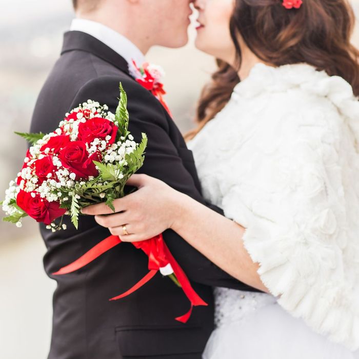 a woman in a faux fur shawl kissing her groom