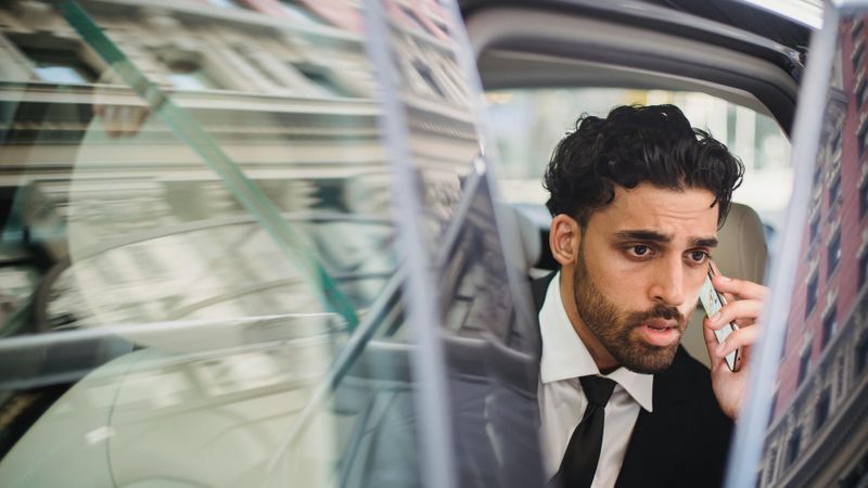 Businessman talking on a phone, leaving a car