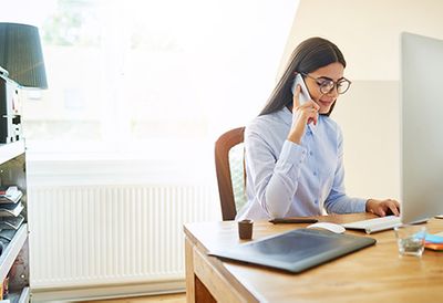 A woman on her phone at her office desk