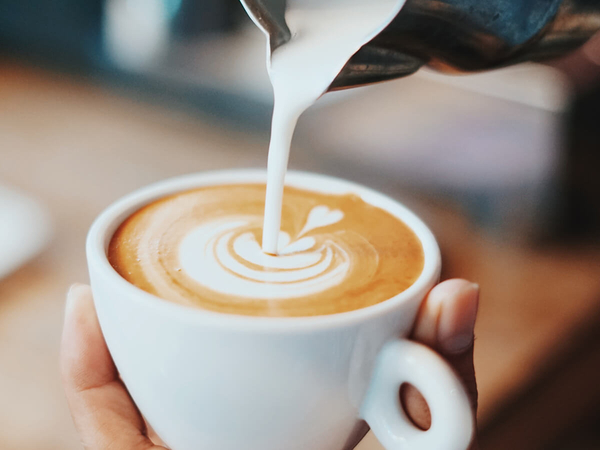 A barista at a coffee shop pouring latte art.