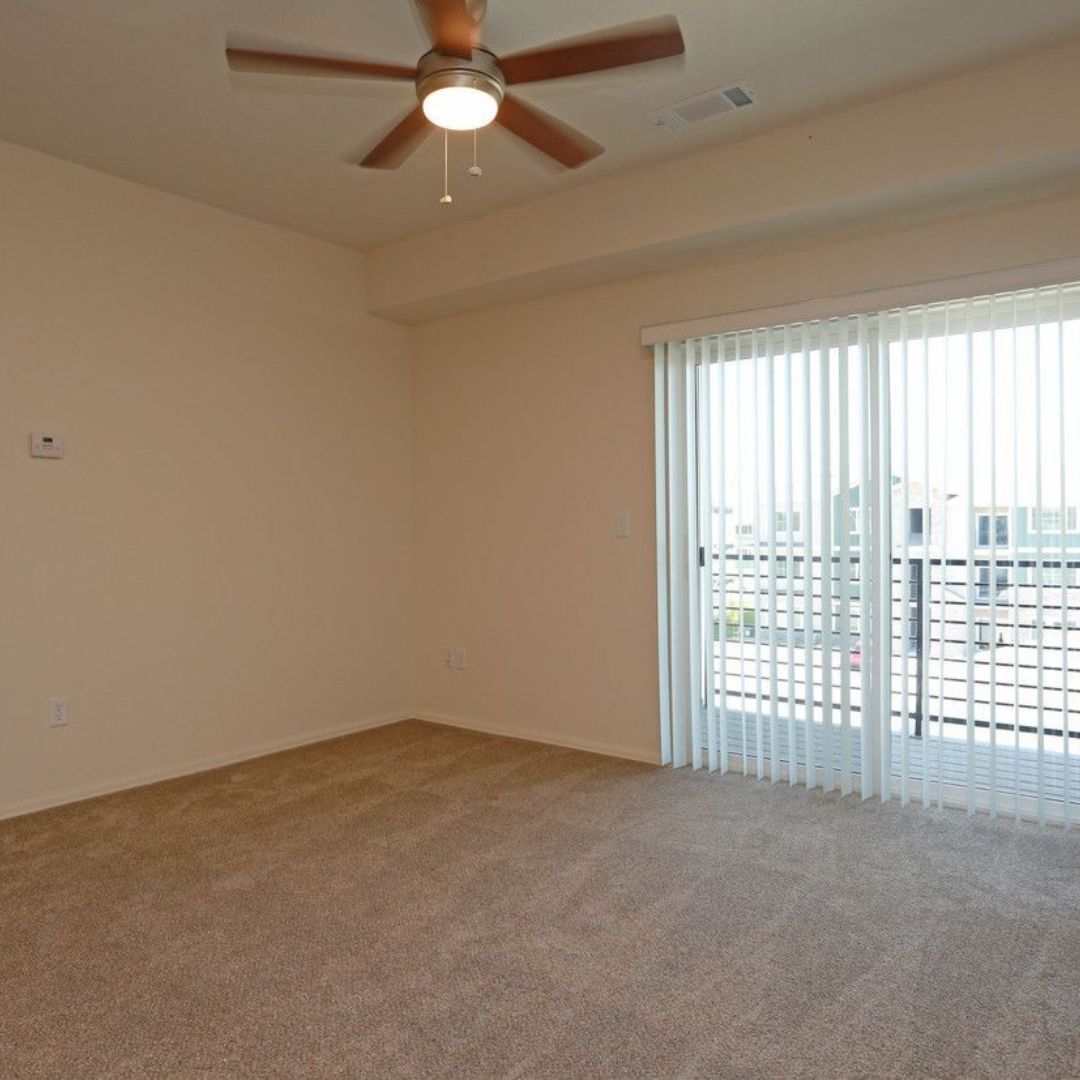 Empty bedroom with a fan and glass doors going outside