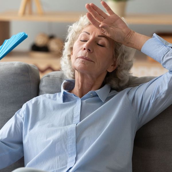 Senior woman feeling overheated in her living room.