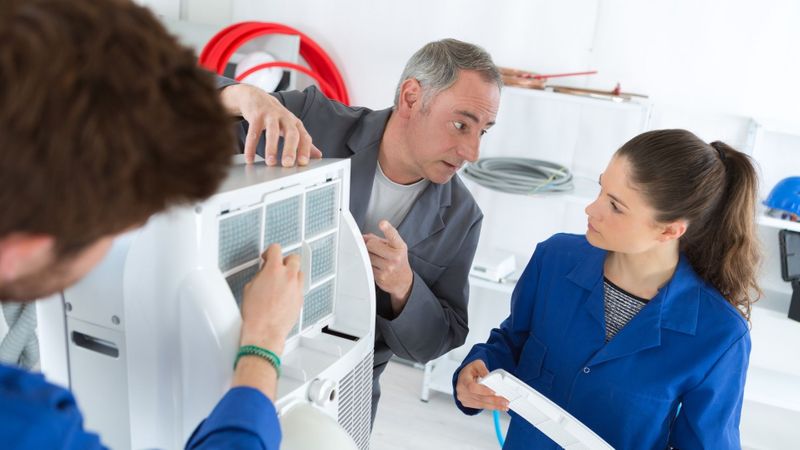A team of technicians examining an HVAC unit's internal components. A team of technicians examining an HVAC unit's internal components.