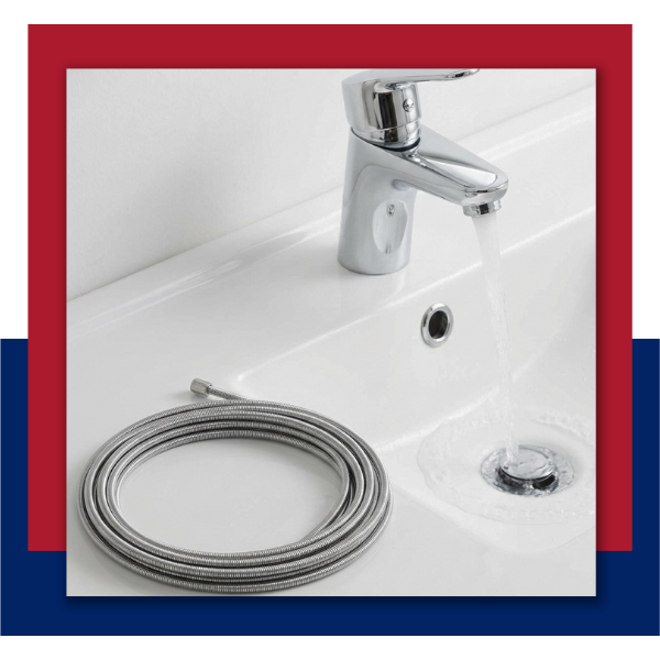 Clean plumbing drain snake tool next to a flowing bathroom sink.