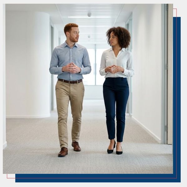 Two business professionals walking in a spotless office hallway.