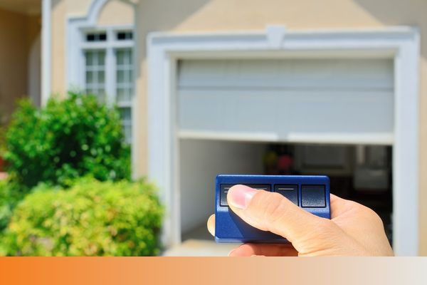 A hand using a garage door opener to open a garage