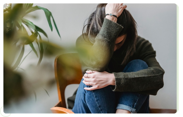 anxious woman curling into ball on chair