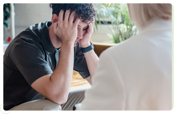 young man with head in hands in front ofg therapist