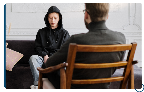 sad teen in hoodie talking to therapist