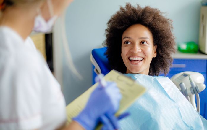 a woman smiling while chatting with a dentist