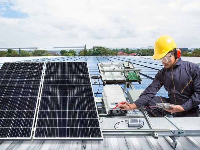 A contractor installs rooftop solar panels.