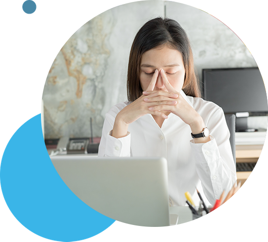 A fatigued woman sitting at a desk with her head in her hands