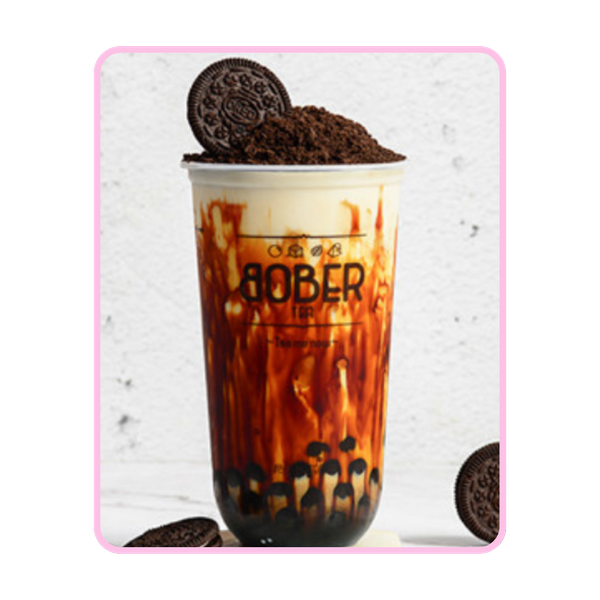 A tall Brown Sugar Boba Milk with signature "tiger stripes" of syrup along the cup. It is topped with a heavy layer of crushed Oreo cookies and one whole Oreo, with several extra Oreo cookies scattered on a white marble surface around the base.