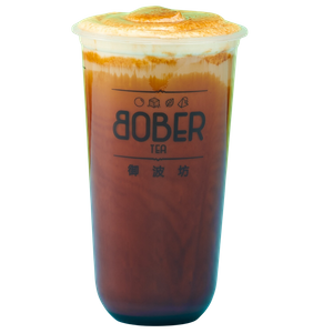 A smooth Brown Sugar Roasted Milk Tea topped with a thick, velvety layer of toasted creme brulee foam. The drink features a deep amber tea base mixed with fresh milk.
