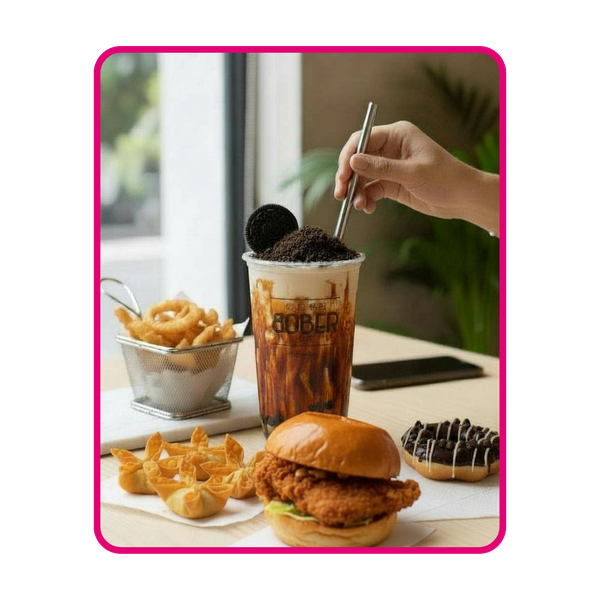 A complete Bober Tea meal spread featuring a Crispy Chicken Sandwich, a side of golden Fried Crab Rangoon, and a basket of crunchy Onion Rings. The meal is paired with a Brown Sugar Oreo Milk Tea and a chocolate-glazed Mochi Donut.