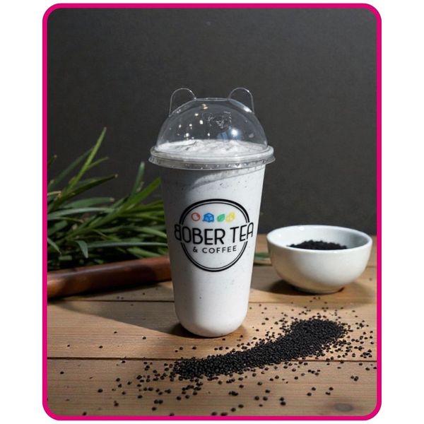 A creamy Black Sesame Latte in a signature cup with a bear-eared lid. The drink is speckled with black sesame seeds