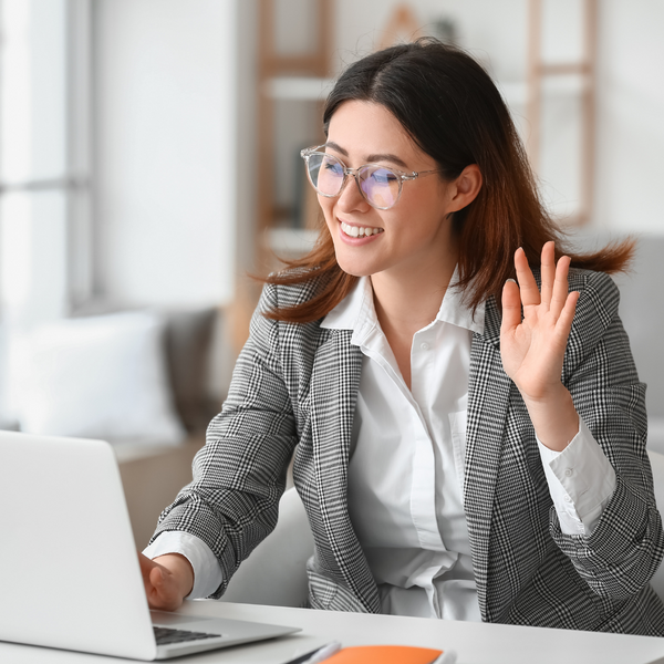 woman waving at a call on her laptop