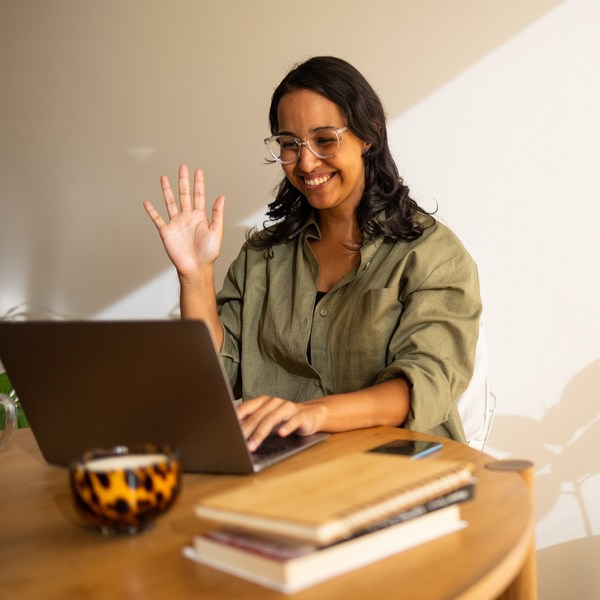 woman waving at a call on her laptop