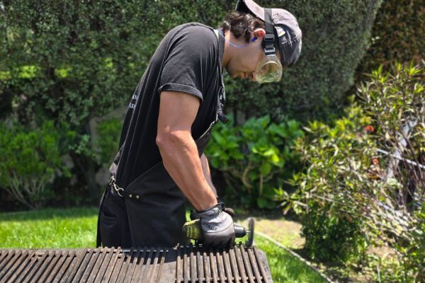 professional grill cleaner using a brush on grates