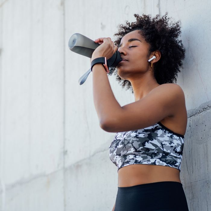 woman drinking water after running