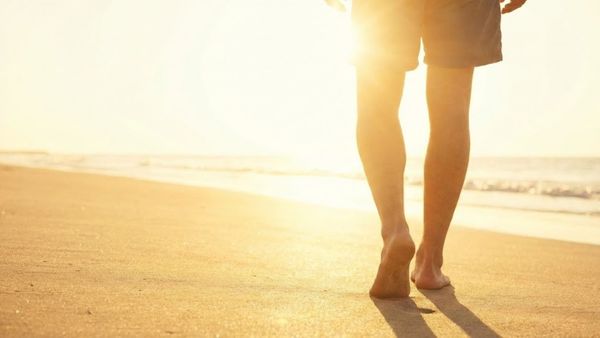 person in athletic shorts walks on a sunny beach person in athletic shorts walks on a sunny beach