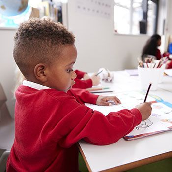 Little boy drawing at school desk