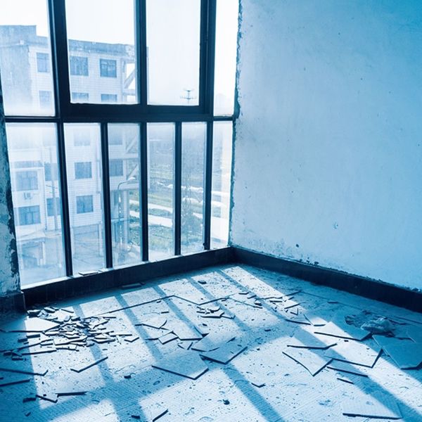 The interior of a damaged room with debris scattered on the floor and visible damage to the walls.