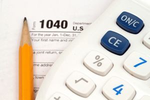 A 1040 tax form with a pencil and calculator on top of it